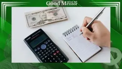 يد تكتب على مفكرة بجوار آلة حاسبة. السواب